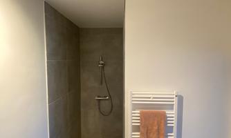A modern bathroom with a shower and a towel warmer. The walls are designed in light and gray colors.