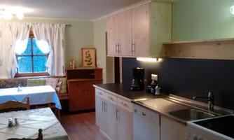 A bright kitchen with wooden cabinets and modern amenities. In the background, there is a dining area with a table and chairs.