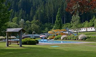 A beautiful pool area with slides and greenery. Surrounded by trees and facilities for relaxation.