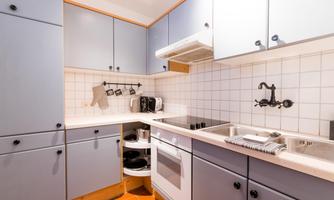 A modern kitchen with gray cabinets and a bright tiled backsplash. The equipment includes a stove, a sink, and kitchen appliances.