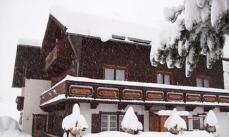 A charming building in winter, covered with thick, white snow. The sky is gray and it is snowing lightly.