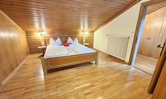 A cozy bedroom with wood paneling and a double bed. The warm lighting creates an inviting atmosphere.