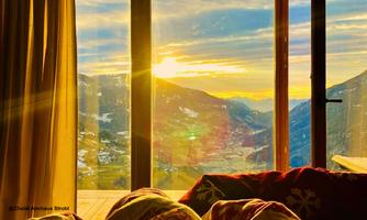 A beautiful view of the mountains at sunrise. The room is cozily furnished and exudes a warm atmosphere.