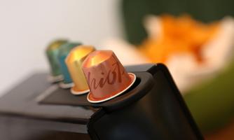 A coffee machine with several colorful coffee capsules. In the background, soft colors and a relaxing atmosphere can be seen.