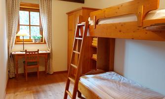 A cozy bedroom with a bunk bed and a small desk. The room is bright and cheerful, with a window that lets in plenty of light.
