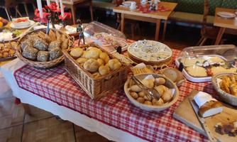 A rich buffet with various rolls, pastries, and sweets. The table is decorated with a red and white tablecloth.
