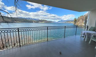 A beautiful view from a terrace of a clear lake and the surrounding mountains. The sky is partly cloudy, and it is a quiet, peaceful place.
