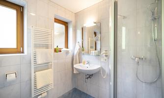 A modern bathroom with bright tiles and a shower. Visible towels and a sink complete the cozy atmosphere.