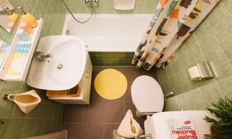 A small bathroom with a bathtub and a shower. The walls are green and there is a colorful shower curtain as well as a yellow rug.