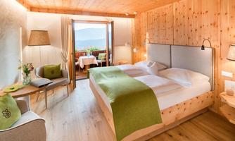 A modern room with wooden decor and two beds. The balcony offers a beautiful view and the furnishings are cozy.