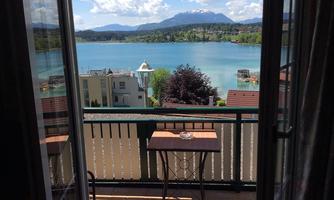 A beautiful view of a quiet lake with mountains in the background. On the balcony stands a small table, perfect for relaxing moments.
