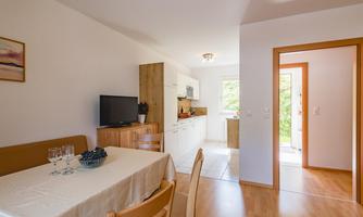 A bright and modern kitchen with a dining table and chairs. A lot of natural light enters the room through the window.