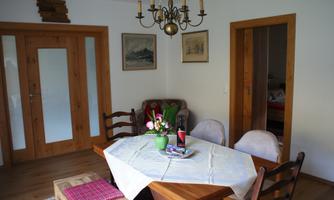 An inviting dining room with a wooden table, chairs, and a skylight. On the table there are flowers and a magazine.