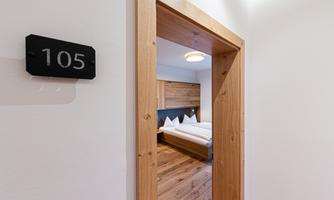 A cozy room with wooden details, visible through the open door. The room number is 105.