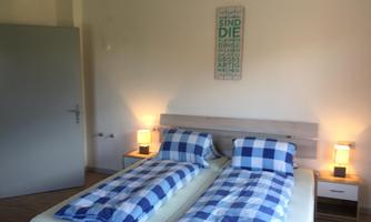 A cozy bedroom with two single beds in a blue and white checkered pattern. Soft lighting from bedside lamps creates an inviting atmosphere.
