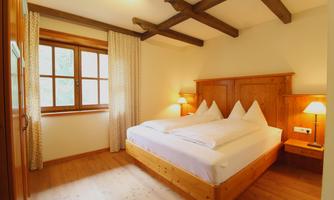 A cozy bedroom with a double bed and wooden decor. As the light gently streams through the window, curtains and nightstands create an inviting atmosphere.