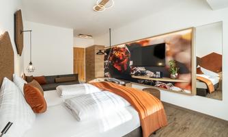 A modern bedroom with a large double bed and an elegant design. The warm colors and the furnishings create an inviting atmosphere.