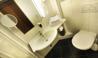A modern bathroom with a sink, towels, and a toilet. The walls are brightly tiled and the floor is dark.