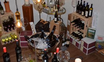 A stylish wine presentation with various bottles in wooden boxes and a cooling device for the wines. The atmosphere is cozy with warm light and glassware.