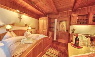 A cozy bedroom with wooden interior and warm light. There is a double bed, a table with wine and glasses, as well as a beautiful flooring.