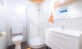 A modern bathroom with a shower and a white sink. The walls are light, and the fittings are functional.