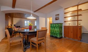 A cozy dining area with a round table and chairs. The room has light walls and a wooden floor, complemented by stylish furniture.