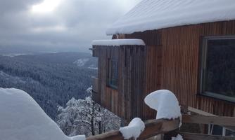 A snow-covered building in the mountains. The sky is overcast and the surroundings are wintry.
