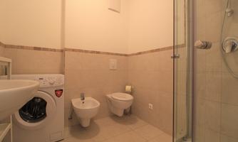 A bright bathroom with a shower, sink, and a washing machine. It is furnished in a modern and functional way.