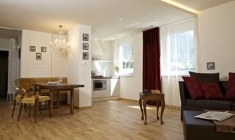 A bright and modern apartment with an open living area. The space features a dining area, a kitchenette, and a cozy sofa.
