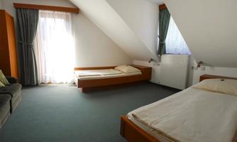 A simple bedroom with two beds and a sofa. Plenty of daylight through the window with curtains.
