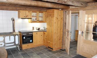 A cozy kitchen with wooden furniture and modern appliances. The room has a rustic charm with exposed beams and tiled flooring.