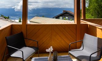A cozy terrace with two chairs and a small table. In the background, mountains and clouds can be seen.