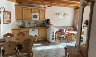A cozy kitchen with wooden cabinets and a dining table. The room is bright and inviting, ideal for sociable meals.