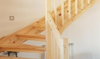 A light wooden staircase with a simple railing. The floor is dark and there is little decoration on the walls.