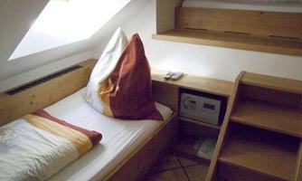 A cozy room with slanted walls and two wooden beds. The room has a bright atmosphere with a window in the roof.
