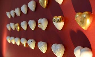 A wall with different ceramic hearts in white and gold. The hearts are arranged in several rows, adding a decorative touch to the room.