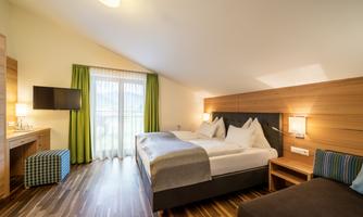 A modern room with a double bed and cozy furnishings. Large windows let in plenty of light and create a bright atmosphere.