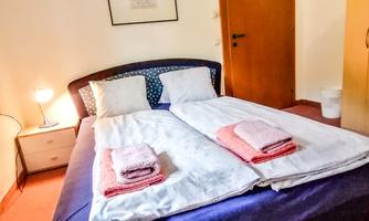 A cozy bedroom with a large double bed and fresh towels. The walls are tastefully designed and the room is well-lit.