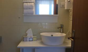 A simple bathroom with a round sink and a large mirror. The room has bright walls and a modern look.