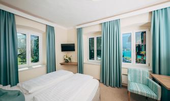A modern room with a double bed and large windows. The bright curtains offer a lovely view of the surroundings.