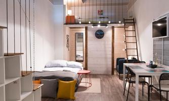A modern loft with a cozy sleeping area and dining corner. The bright decor and staircase create an inviting atmosphere.