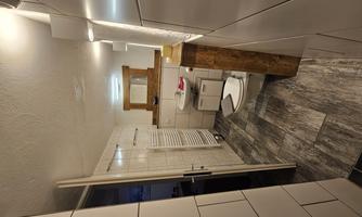 A modern bathroom with light tiles and wood decor. It contains a toilet, a sink, and a mirror.