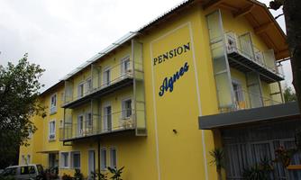 A bright yellow building with the inscription "Pension Agnes". There are several balconies and small plants in front of the entrance.