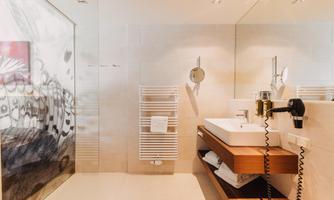 A modern bathroom with a stylish decor. There is a sink, a hairdryer, and elegant wall coverings.