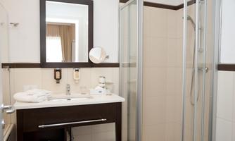 A modern bathroom with a shower and a large mirror. Fresh towels are ready on the washstand.