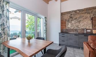 A modern designed living space with a wooden table and black chairs. Large windows offer a view of the outdoors and let in plenty of light.