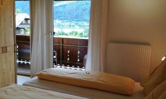 A cozy room with two beds and a view of the mountains. The balcony is well visible through large windows.