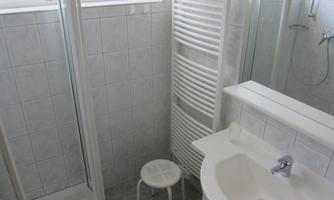 A modern bathroom with a shower cubicle, a sink, and a towel warmer. The interior is designed to be bright and functional.