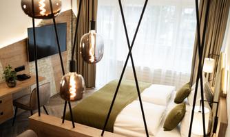 A modern hotel room with double beds, elegant decor, and soft lighting. The large windows provide plenty of daylight and a welcoming atmosphere.
