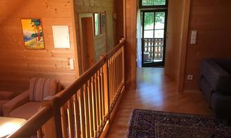 A bright wooden interior with a cozy seating area. The room leads to a balcony with a view outside.